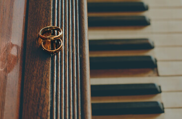 wedding rings lie on the piano, a dark brown tree and black and white keys