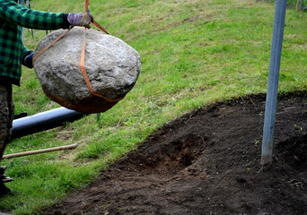 safe handling of a very heavy granite boulder with a crane, the stone is picked up and tied with...