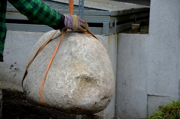 safe handling of a very heavy granite boulder with a crane, the stone is picked up and tied with...