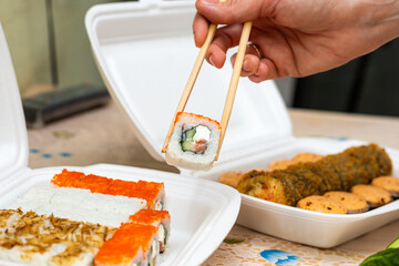 sushi and rolls with home delivery, eat at the table against the background of food