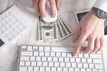 Man typing in keyboard. Dollar banknotes on the desk