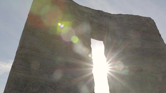 Rotating around a big stone with a sun flare in Stonehenge
