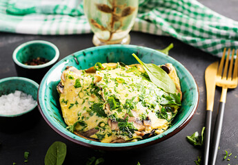 Spinach and mushroom omelette. Frittata made of eggs, mushrooms and spinach. Italian cuisine.