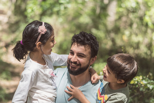 Father with son and daughter playing in pine forest