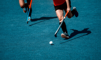 Field hockey player, in possesion of the ball, running over an astroturf pitch, looking for a team...