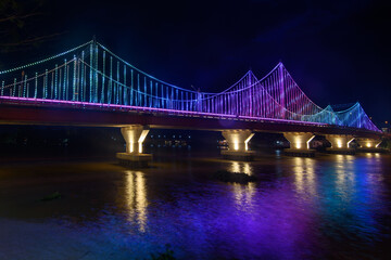 Fototapeta na wymiar The scenery of the Tapi river bridge with the colorful light decoration at dusk in Surat Thani province, Thailand.