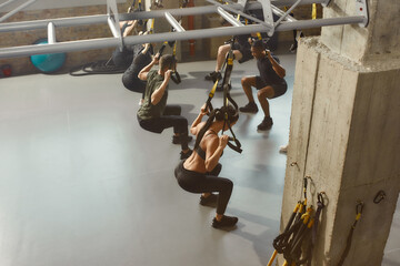 We can do hard things. Group of sportive people doing fitness training exercises at industrial gym. Push-up, group workout concept