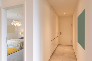 Interior of a long corridor of an apartment. At the bottom a closed door
