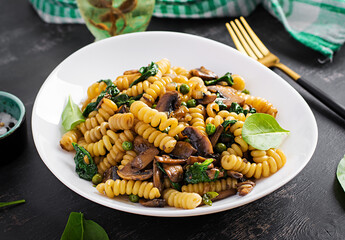 Fusilli pasta with spinach and mushrooms on a white plate. Vegetarian / vegan  food. Italian cuisine.
