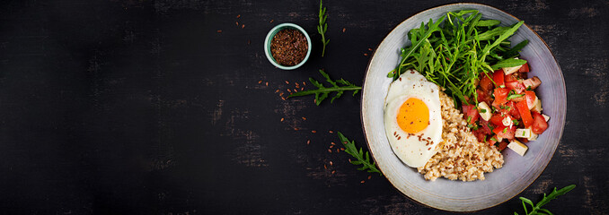 Breakfast oatmeal porridge with fried egg, tomato salad, arugula and flax seeds. Healthy balanced food. Top view, banner,  copy space