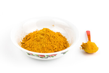 Turmeric powder in a white bowl and plastic spoon over white background. 