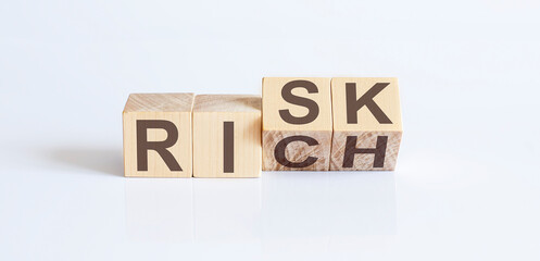 Wood cube word risk or rich on wooden table white background.