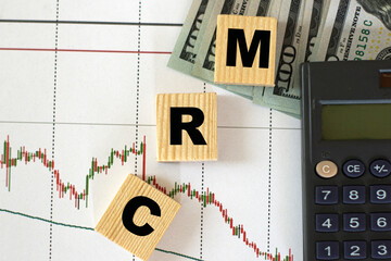 CRM word on cubes on the background of calculator, money and graphics