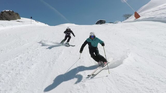 Two professional male skiers show perfect slalom turns . Very exact formation skiing on steep ski slope. Sixty p slomoltion