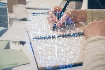 Double exposure of writing hand on background with brain hologram. Concept of learning.