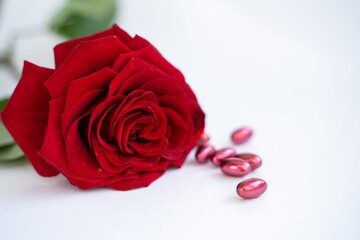 care natural concept. Red pills on white background with red rose .
