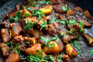 Close-up of delicious chicken curry strips stewed with porcini in sour cream sauce sprinkled with finely chopped parsley on a skillet, authentic recipe, horizontal view from above