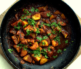 Close-up of delicious chicken curry strips stewed with porcini in sour cream sauce sprinkled with finely chopped parsley on a skillet, authentic recipe, horizontal view from above