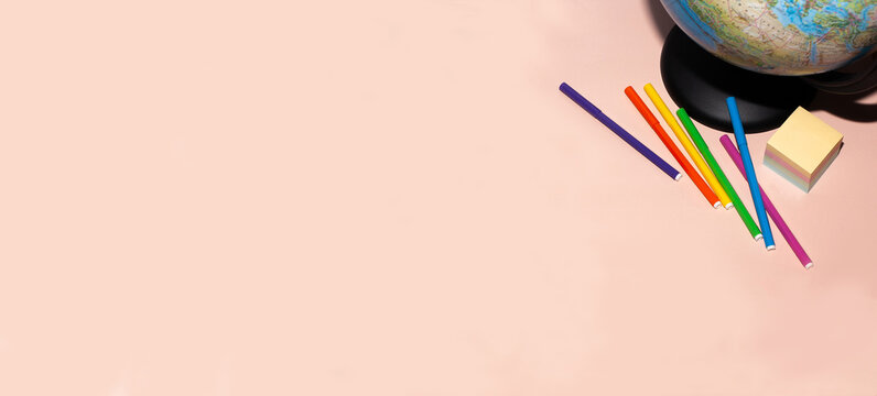 Colored pens and a block for writing are on the table near the part of the globe. Back to scool .Flat lay. Top view.