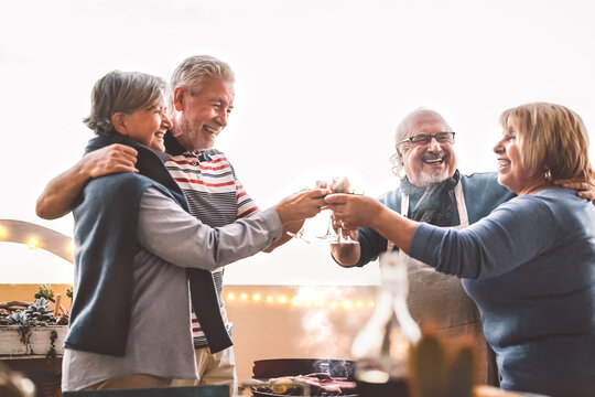 Happy Senior Friends Drinking Red Wine At Barbecue On House Patio - Mature People Cheering And Dining Together At Bbq Party - Food And Elderly Friendship Lifestyle Concept