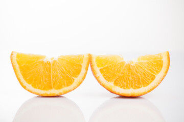 Two slices of sliced ​​orange on a white background with reflection at the bottom. Isolated...