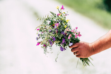 Main d'un homme tenant un bouquet de fleurs champêtres © PicsArt