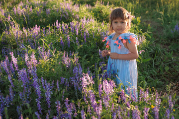 Little girl is smelling the flower outdoors