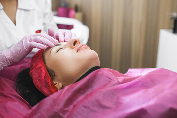 Cosmetologist making a face massage to her patient and a face mask. Anti-ageing and smoothing procedure in a beauty salon. Doctor in a cosmetological clinic making a treatment of skin care