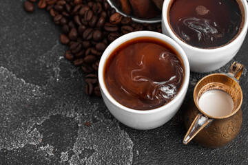 White coffee cup with with beans on dark surface