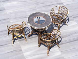 old wicker furniture, table with chairs on marble gray tiles