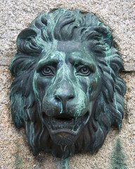Obraz premium Antique bronze lion mask fixed to a granite block wall