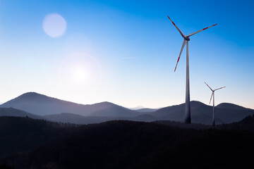 Two Wind Turbines under Blue Sky in a Landscape with Hills