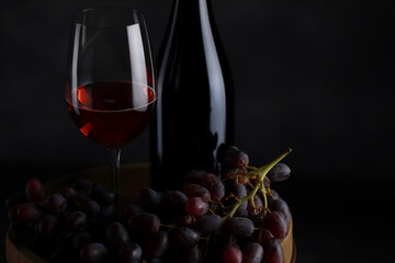 The red wine in the glass, along with a bottle of wine made from red grapes, is laid on a wooden floor and a beautiful backdrop. Ready for partying