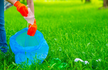 A volunteer puts a used medical mask in a trash bag. Garbage collection in nature