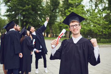 Man graduate is smiling against the background of university graduates.