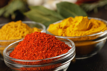 Turmeric powder in glass bowl on wooden table close up