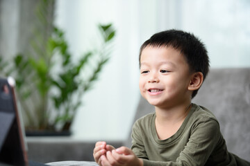 Asian boy with a cute face and good temper is looking and smiling at the camera in front of the tablet. While talking to friends via video call.