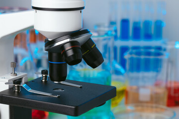 Scientific laboratory with microscope and test tubes with samples, close up photo