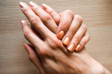 two female hands . manicure . gel Polish on women's hands in the form of snakeskin with orange...