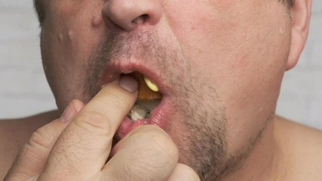 Fat man eating greasy sandwich of bread and butter close up.