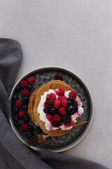 Topview image of oatmeal pancakes topped with yogurt and berries