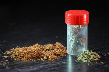 Small box full of cannabis and tobacco on a black background. Marijuana legalization. Medical cannabis. Drug addiction.