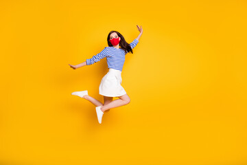 Fototapeta na wymiar Full length photo of carefree dreamy girl jump raise hands wear medical red mask style stylish trendy clothes gumshoes isolated over bright shine color background