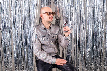 Fototapeta na wymiar The 90s singer, wearing a silver shirt and leather pants, sings songs in the studio isolated on a glittering backdrop