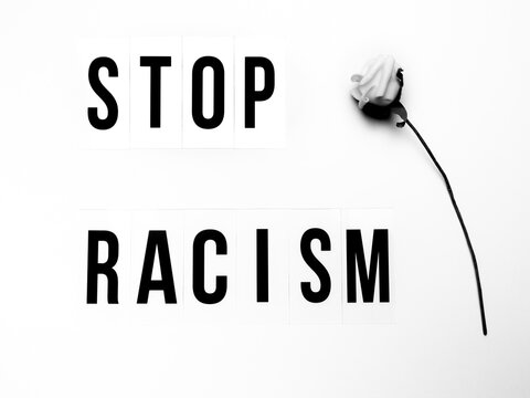 Capital letters with the text stop racism and a white rose against white background