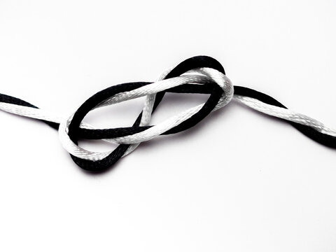 A knot with a white thread and a black thread against a white background