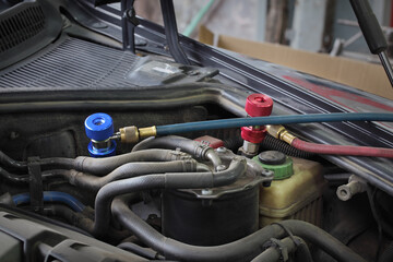 Charging of air condition unit at modern car, closeup of equipment conected to car engine, red and blue clutch couplings