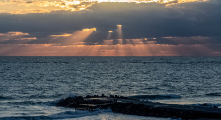 The beauty of the sunrise. The bright rays break through the clouds and descend to the stormy Black Sea.