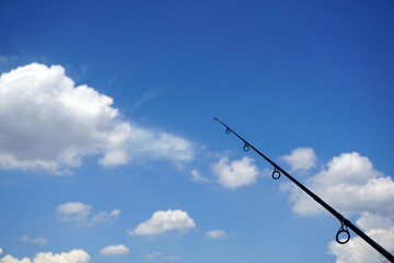 Obraz premium Fishing rod and cloudy blue sky background
