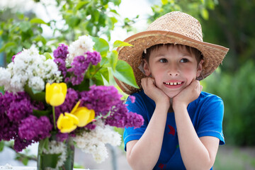 Fototapeta premium Funny child in panama with a bouquet of flowers. Happy boy in the summer.